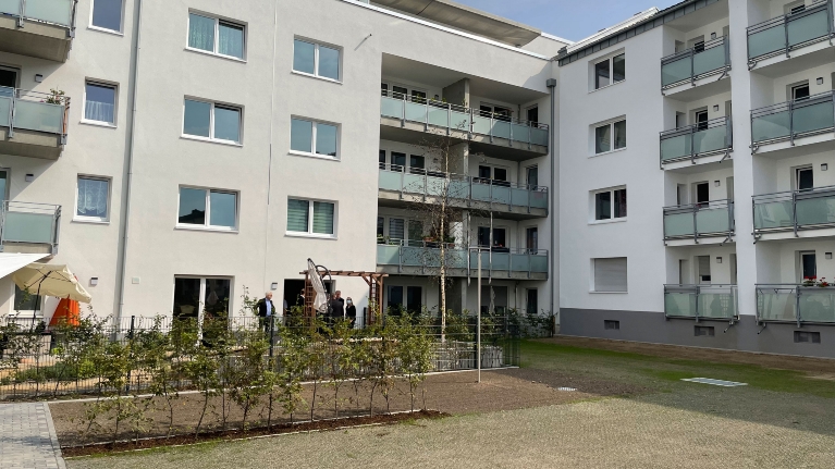 Innenhof eines Wohnblocks mit einer lichten Hecke und einer Parkfläche