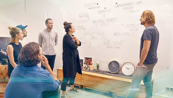 Mehrere Mitarbeiter von Kerbholz in einer Besprechung vor einem Whiteboard mit Notizen