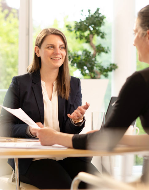 Beratungssituation mit zwei Frauen, die sich am Schreibtisch gegenüber sitzen