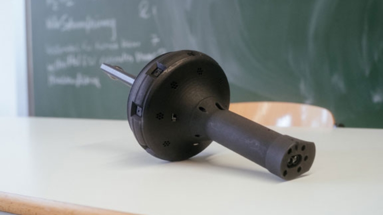 Thermoscan-Messgerät liegt auf einem Tisch. Optisch erinnert es an eine Fackel.