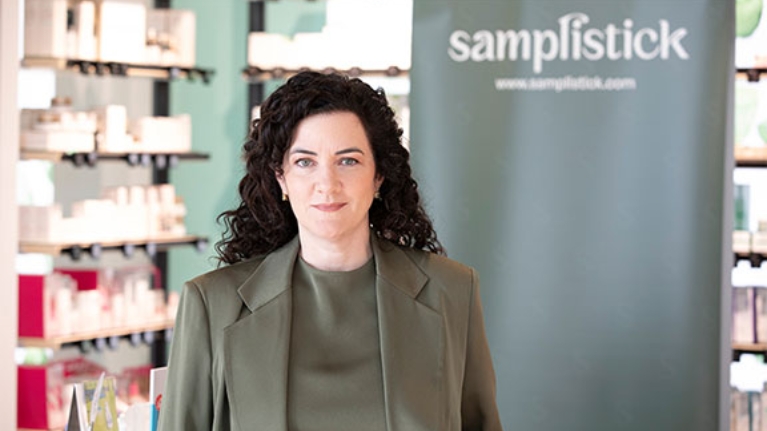 Die Gründerin steht in einem Geschäft, im Hintergrund ein Werbebanner.