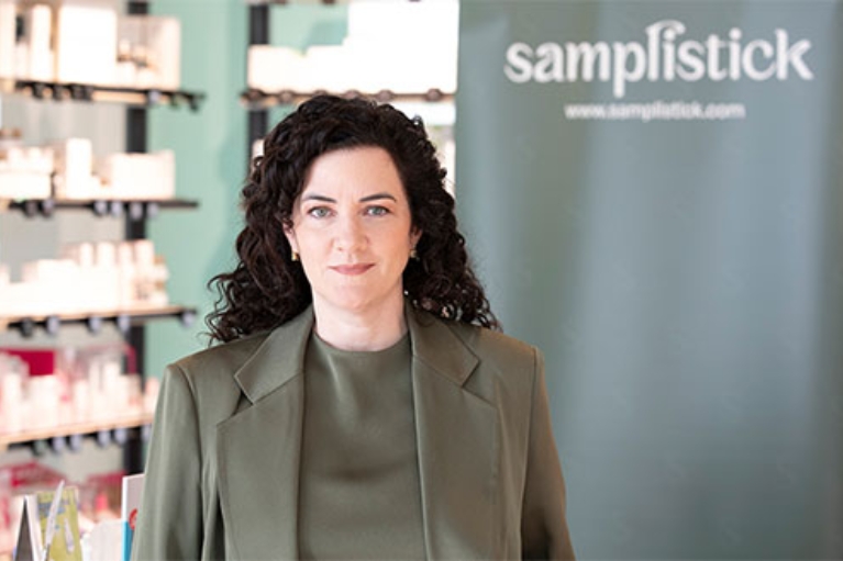 Die Gründerin steht in einem Geschäft, im Hintergrund ein Werbebanner.