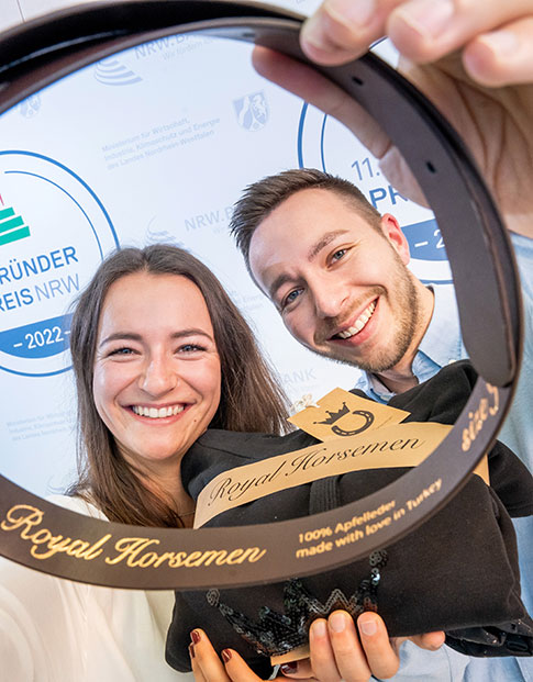 Die Nominierten des Gründerpreises 2022 Julia Schuster und Robin Schuster der RH Royal Horsemen GmbH halten Produkte der nachhaltigen Modelinie für den Reitsport in ihren Händen.
