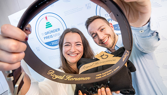 Die Nominierten des Gründerpreises 2022 Julia Schuster und Robin Schuster der RH Royal Horsemen GmbH halten Produkte der nachhaltigen Modelinie für den Reitsport in ihren Händen.