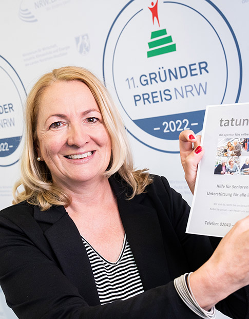 Die Nominierte des Gründerpreises 2022 Sabine Paschen-Schnarkowski der Initiative tatundrat steht vor der Medienwand und hält eine Papier mit Informationen zu der Initiative hoch.