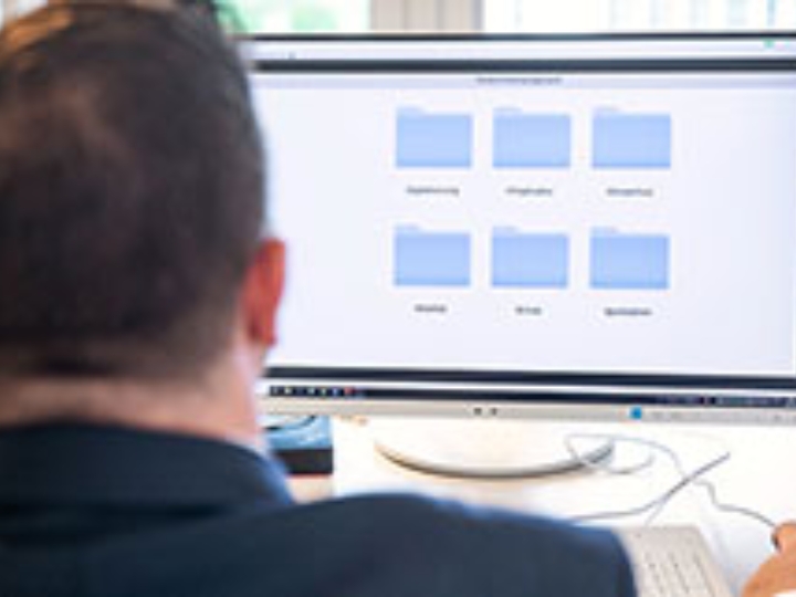 Ein Mann sitzt vor einem Monitor, der ein Programm zum Fördermittelmanagement zeigt.