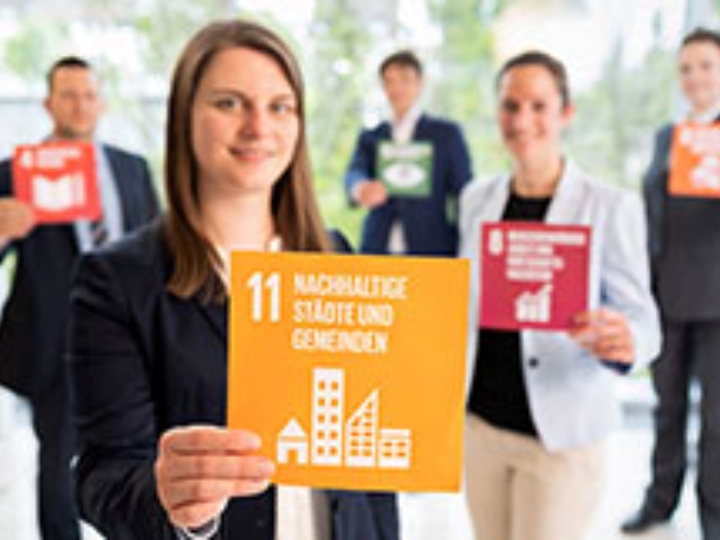 Mitarbeiter der NRW.BANK halten Karten mit Symbolen der Sustainable Development Goals hoch.