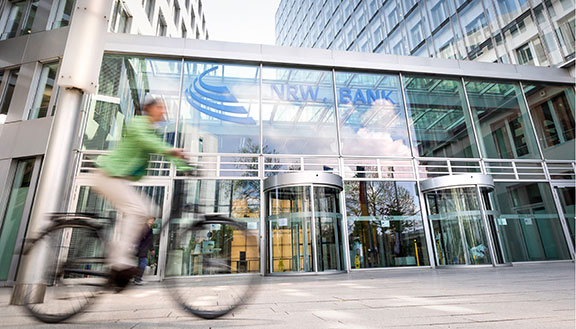 Fahrradfahrerin vor dem Firmengebäude der NRW.BANK.