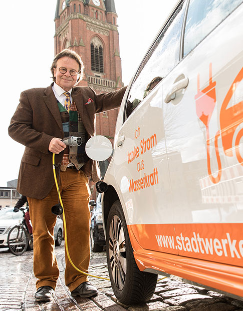 Dr. Ronald Heinze, Geschäftsführer der Stadtwerke Rhede, lädt ein Elektrofahrzeug.