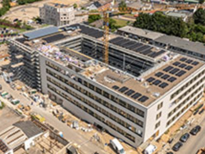 Luftaufnahme einer großen Rathaus-Baustelle mit Kran und umliegender Stadtinfrastruktur.