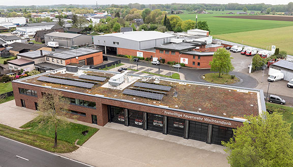 Feuerwehrhaus mit Flachdach, Solaranlagen und großen Toren, im Gewerbegebiet gelegen.
