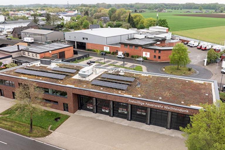 Feuerwehrhaus mit Flachdach, Solaranlagen und großen Toren, im Gewerbegebiet gelegen.