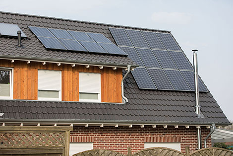 Das Bild ein Hausdach mit einer Solaranlage. Die NRW.BANK bietet Förderprogramme für Modernisierunung und energetische Sanierung an. 