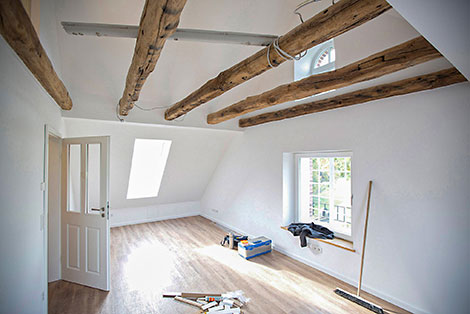 Heller Raum mit Holzboden und Naturbalken an der Decke