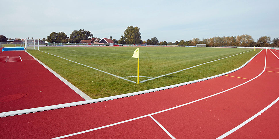 Fußballplatz mit roter Laufbahn außen herum