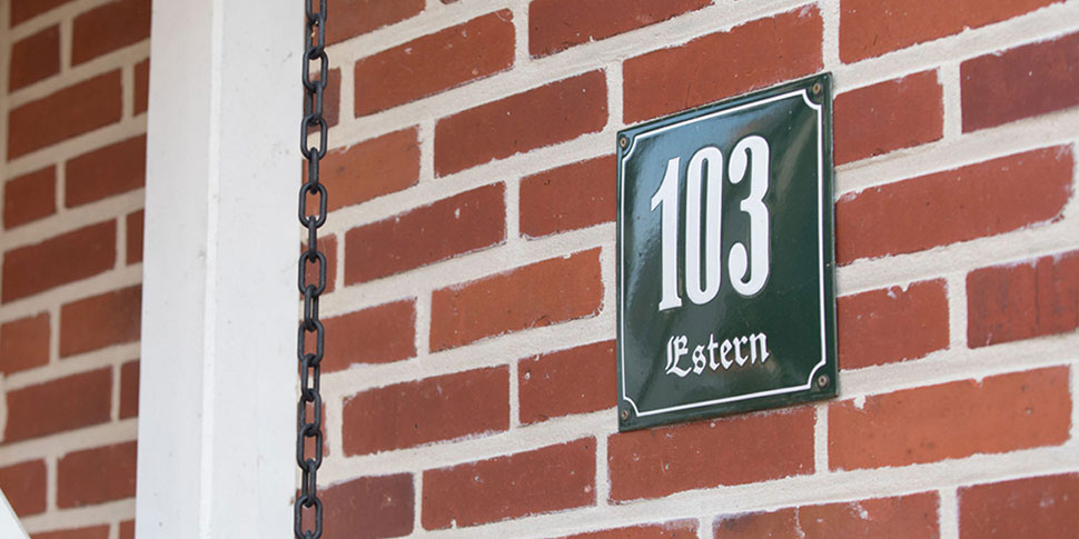 Ausschnitt einer roten Backsteinfassade mit der Hausnummer 103