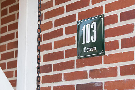 Eingangsbereich eines roten Ziegelhauses mit der Hausnummer 103.