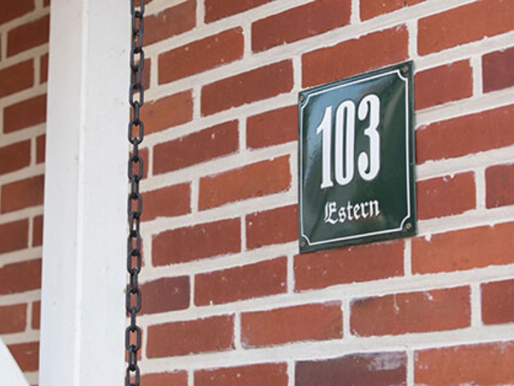 Ausschnitt einer roten Backsteinfassade mit der Hausnummer 103