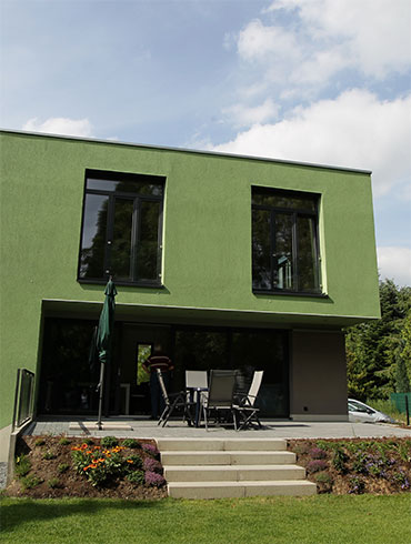 Ein Bungalow mit grüner Hauswand und Terrasse