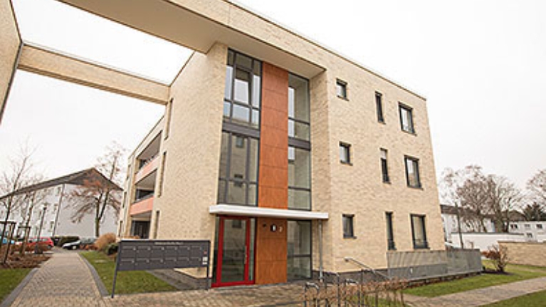 Eingangsbereich des Schützenhofs Lünen, ein modernes Wohnquartier, helle Fassade