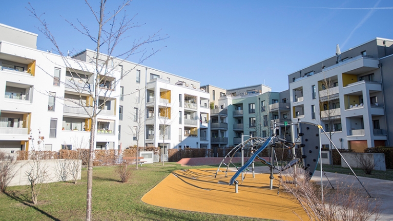 Das Carlswerkquartier in Köln: heller, moderner Wohnblock, davor ein Park mit Spielplatz