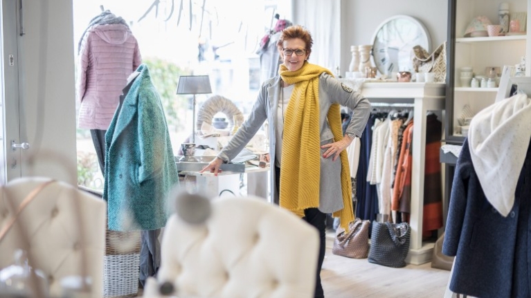 Petra Hustadt steht in ihrem Geschäft Herzstück umgeben von Kleidung und Wohnaccessoires