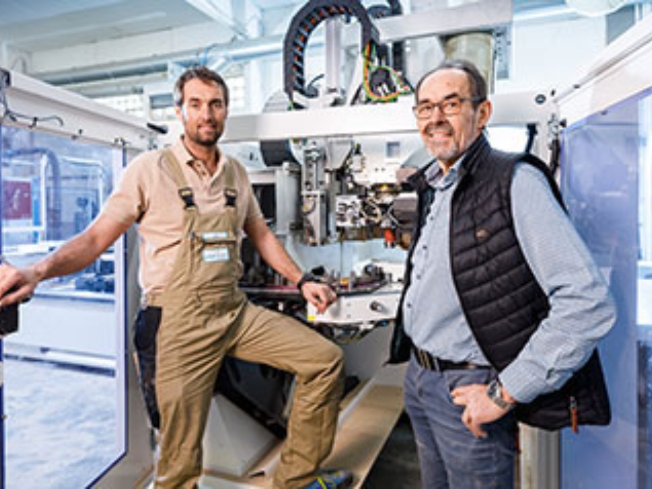 Jan und Josef Hüser, Geschäftsführer der Hüser Michels GmbH, vor einer großen Maschine in ihrer Firma