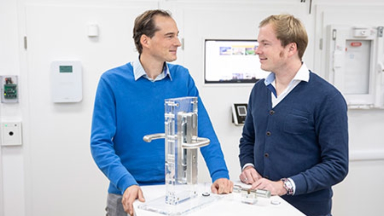 Tino und Dennis Konnertz, Geschäftsführer von Konntec, vor dem Modell eines Türschlosses