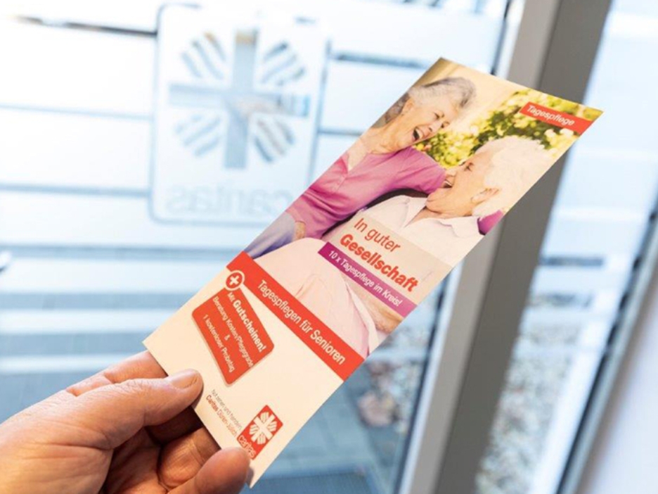 Eine Broschüre mit Infos zum tagespfelegeangebot der Caritas wird in deiner Hand gehalten