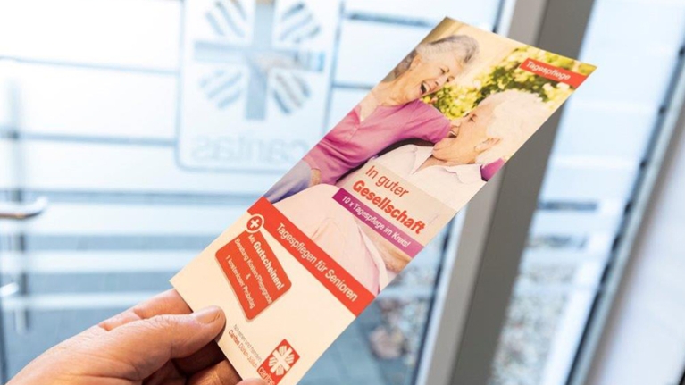 Eine Broschüre mit Infos zum tagespfelegeangebot der Caritas wird in deiner Hand gehalten