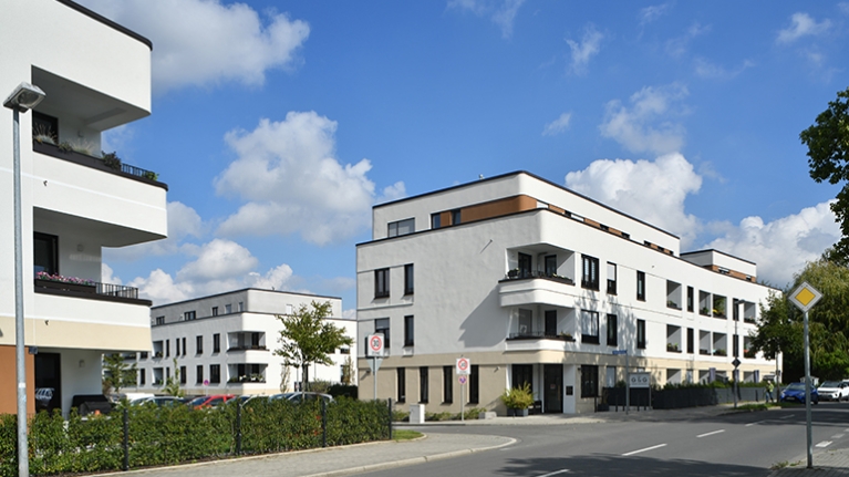 Eine Neubausiedlung mit heller Fassade und abgerundeteten Ecken
