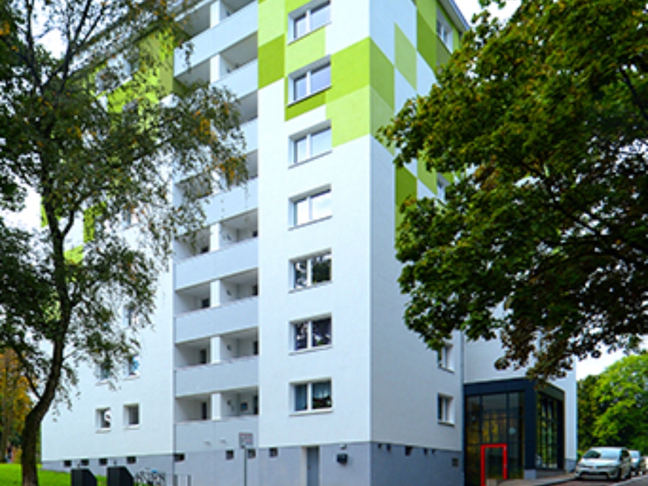 Ein Hochhaus mit weißer Fassade und grünen Dekoelementen