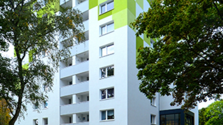 Ein Hochhaus mit weißer Fassade und grünen Dekoelementen