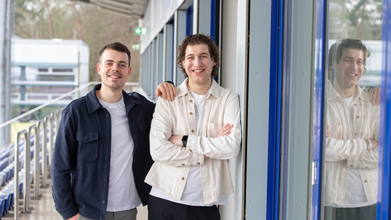 Die Geschäftsführer von Kiman Sport stehen für ein Foto auf einer Tribüne der Sporthochschule Köln