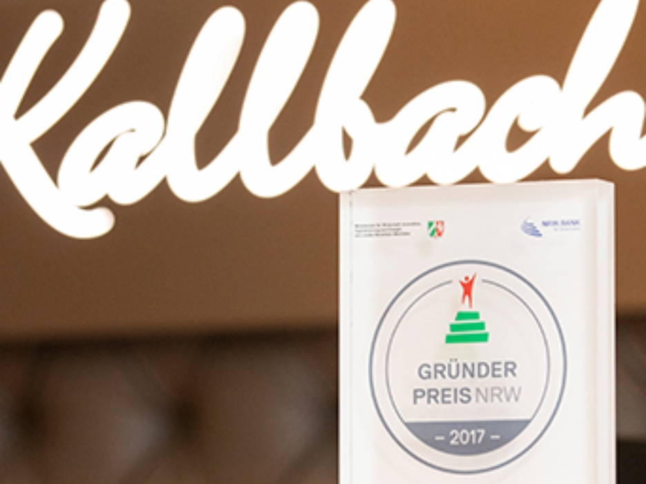 Die Trophäe des 2017 gewonnenen GRÜNDUNGSPREIS NRW steht vor dem Logo des Hotels Kallbach