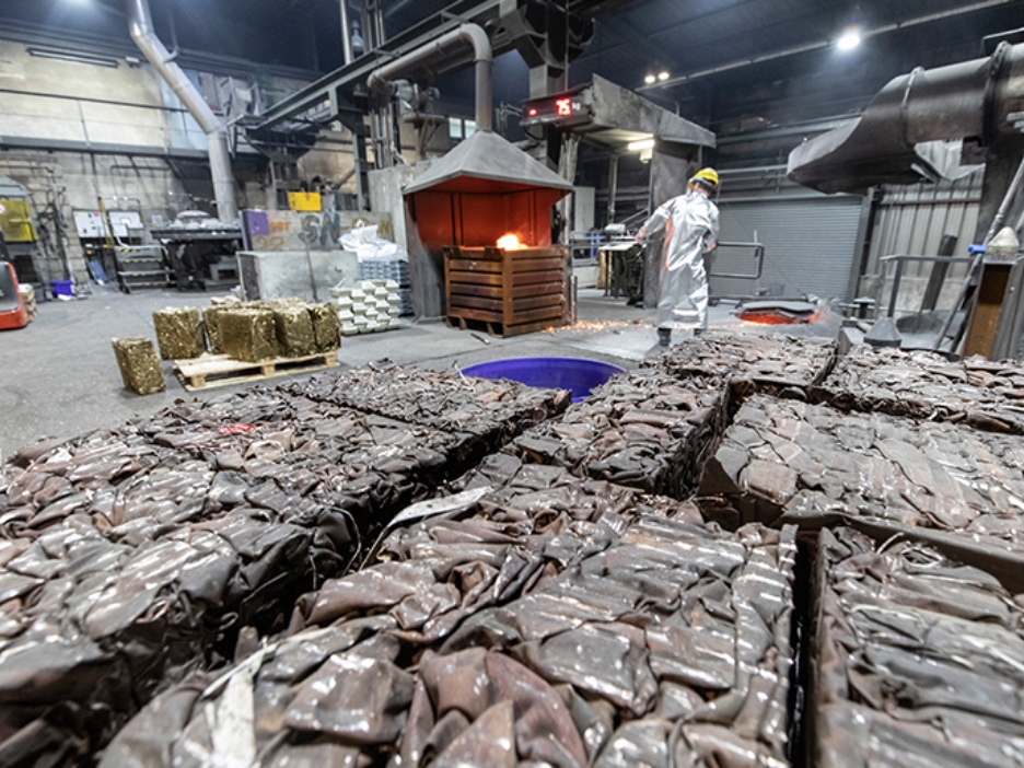 Mann in silbernem Hitzeanzug steht an Metallschmelze