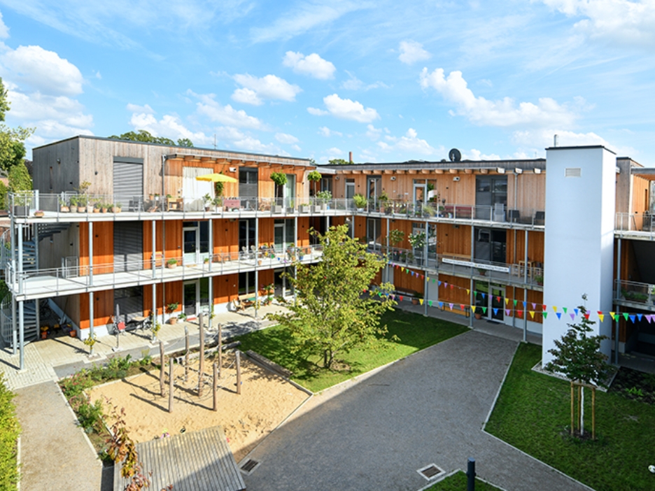 Innenhof des Wohnprojekts TRIALOG in Hilden mit Spielplatz und bunten Fahnengirlanden.