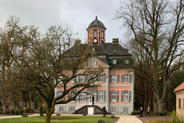 Außenansicht des Barockschlosses Arff in Köln mit Parkanlage im Vordergrund